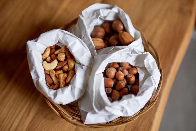 Ansicht von oben Verschiedene Arten von Nüssen auf dem Tisch in einer Papiertüte auf Holzhintergrund Einkaufskonzept Lebensmittelgeschäft Nüsse Lieferung Zero Waste Food Shopping Copy Space