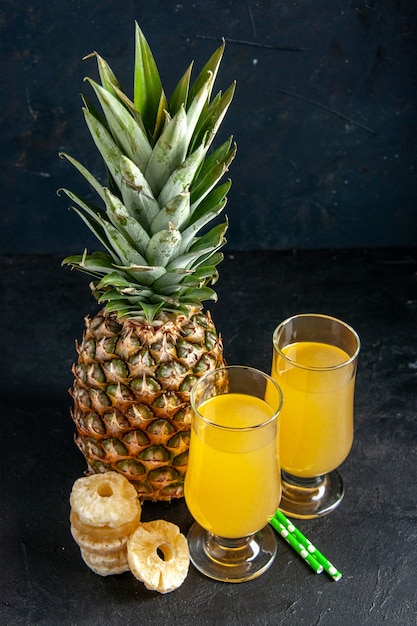 Ansicht von unten frische Ananas trockene Ananasscheiben Pipetten Ananassaft in Gläsern auf dunklem Hintergrund