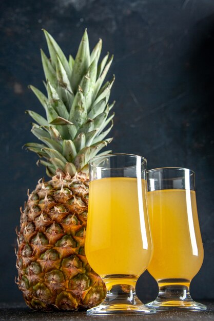 Ansicht von unten frischer Ananas-Ananas-Saft in Gläsern auf dunklem Hintergrund