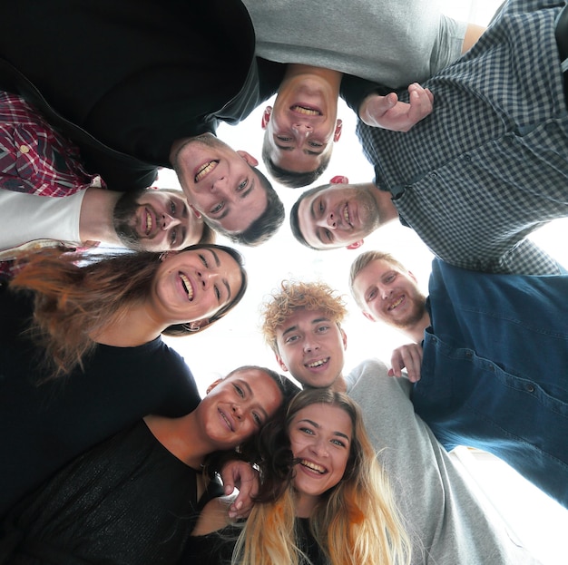 Foto ansicht von unten gruppe lächelnder junger menschen, die in einem kreis stehen