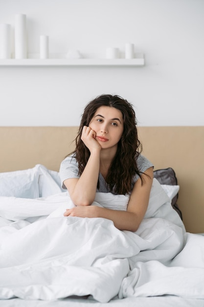 Ansiedad matutina Problema de insomnio Estrés de fin de semana Pensativo inquieto cansado aburrido molesto mujer sentada en la cama sola en el dormitorio de luz