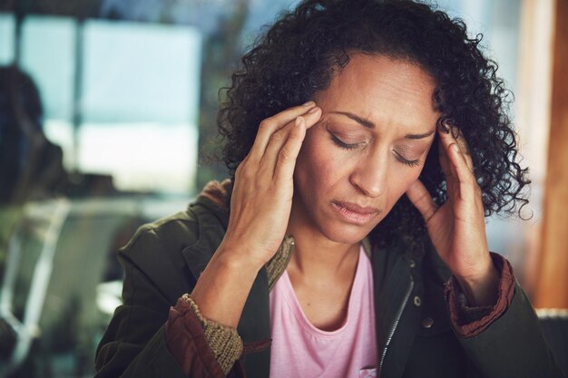Foto ansiedade mulher negra madura com dor de cabeça ou estresse e em casa depressão ou esgotamento saúde mental ou cuidados de saúde e mulher exausta ou cansada com as mãos na cabeça no fundo de sua casa