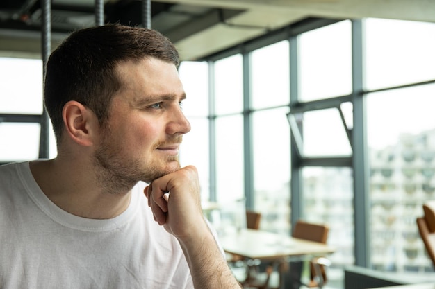 Foto ansprechender junger mann schaut aus dem fenster im büro