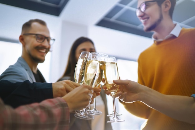Anstoßende Gläser mit Champagner Fröhliche Mitarbeiter, die ihren geschäftlichen Erfolg feiern