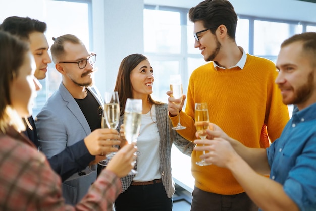 Anstoßende Gläser mit Champagner Fröhliche Mitarbeiter, die ihren geschäftlichen Erfolg feiern