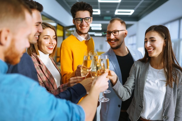 Anstoßende Gläser mit Champagner Fröhliche Mitarbeiter, die ihren geschäftlichen Erfolg feiern