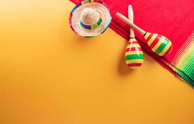 Antecedentes festivos del Cinco de Mayo hechos de rayas de manta mexicana maracas o sarape de poncho y sombrero sobre fondo amarillo