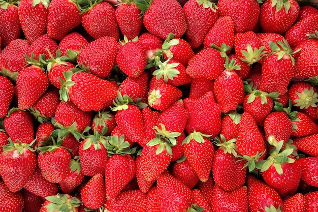 Antecedentes de fresas rojas frescas y brillantes con hojas verdes en el mercado