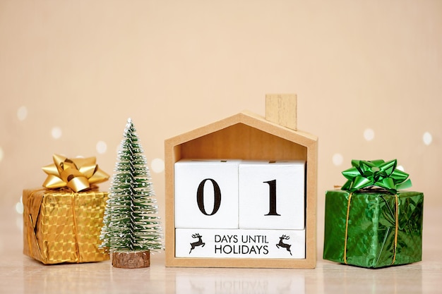Antecedentes navideños un día antes de las vacaciones. Casa, árbol de Navidad y regalos en una mesa de madera.