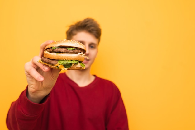Antecedentes. Primer plano de una hamburguesa en manos de un joven.