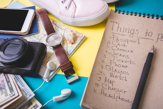 Antecedentes para un viaje de planificación: relojes, zapatillas, mapa, dólares, gafas, cámara, auriculares, pasaporte