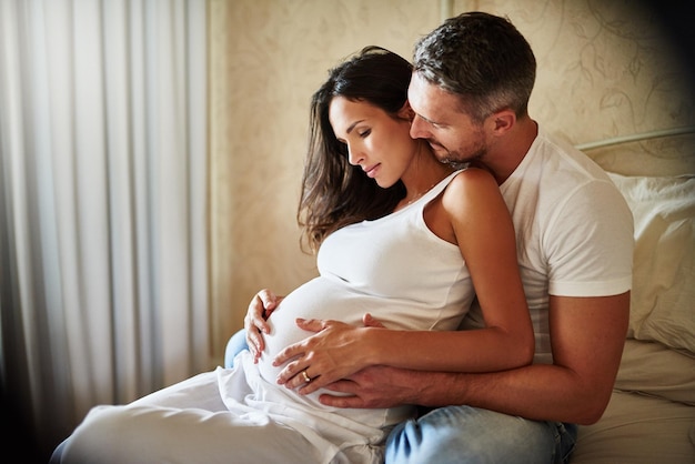 Antecipando sua nova adição Foto de um marido e uma esposa grávida sentados juntos em um quarto