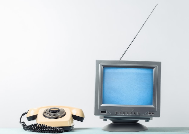 Antena antiquado receptor de tv retrô e telefone giratório na parede branca