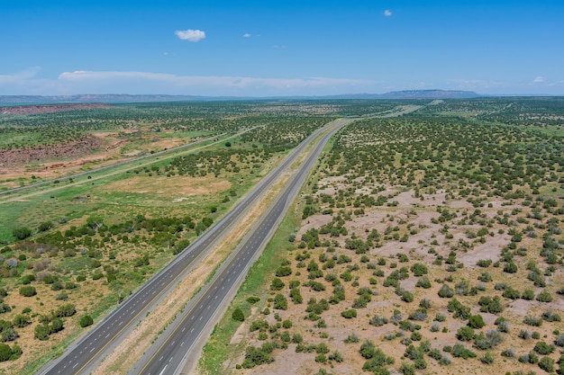 Antena de la carretera del desierto de una nueva carretera de dos carriles rodeada por el paisaje desértico de Arizona, EE.