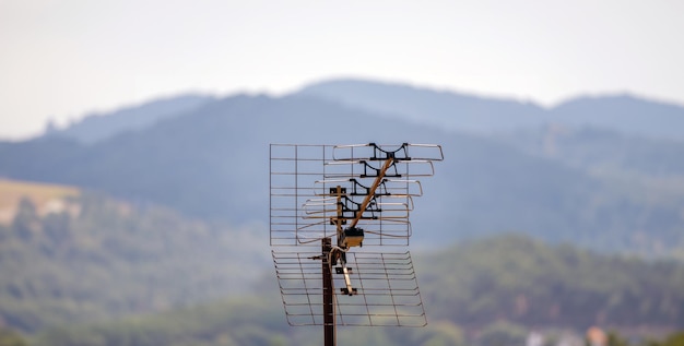 Antena de televisão aérea ao ar livre no telhado de uma casa em uma cidade rural cercada por montanhas