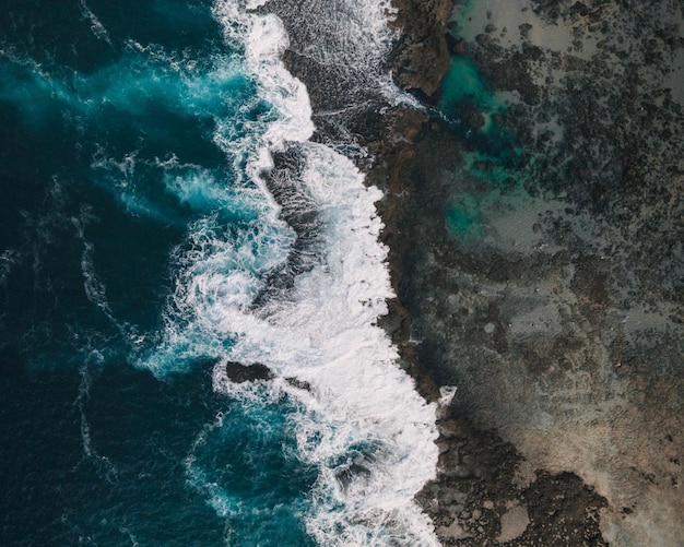 Antena Hermoso paisaje de una playa con olas azules, acantilados rocosos