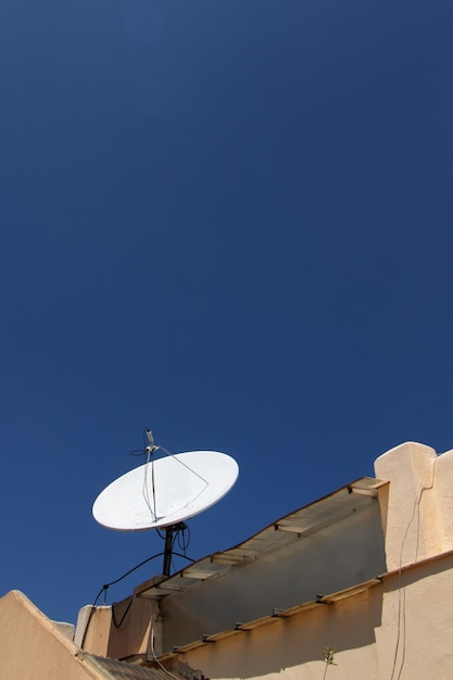 Antena parabólica en el techo con cielo azul profundo