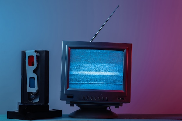 Antena, receptor de tv anticuado con cassette de video de gafas estéreo anaglifo en luz de neón degradado azul rosa Retro entretenimiento de los medios de comunicación de los años 80