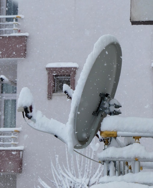 Antena satelital bajo la nieve en el techo nieve acumulada en el techo en tormenta de nieve de invierno