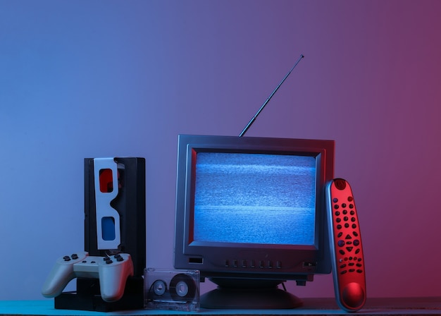 Antenne altmodischer Fernsehempfänger, Anaglyphenbrille, Uhr, Audio- und Videokassette, Gamepad, Fernbedienung in rosa blauem Neonlicht mit Farbverlauf. Retro-Welle