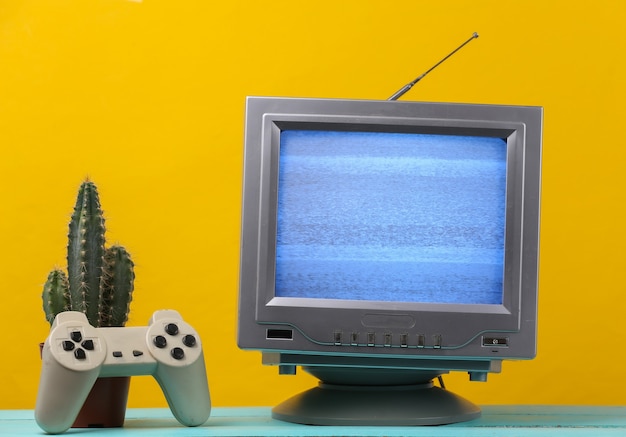 Antenne altmodischer Retro-TV-Empfänger mit Gamepad, Kaktus auf Gelb.