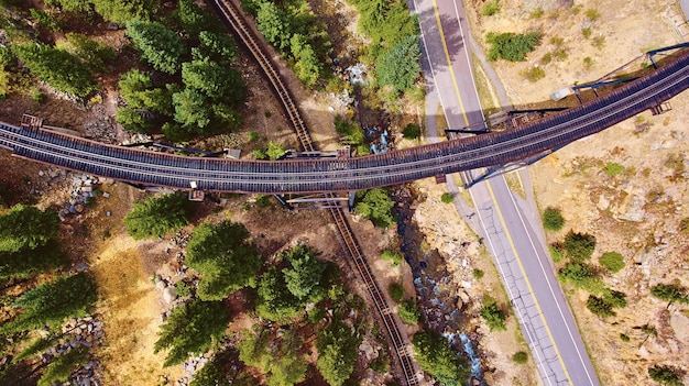 Antenne von Bahngleisen, die Gleise und Straße in der Wüste überqueren