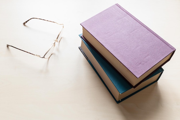 Anteojos y dos libros en blanco sobre tablero de luz