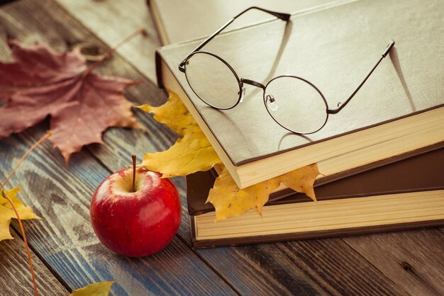 Foto anteojos con libro y hojas de otoño en la mesa