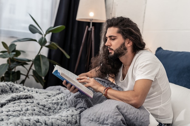 Antes de dormir. homem bonito e simpático lendo seu livro favorito antes de adormecer