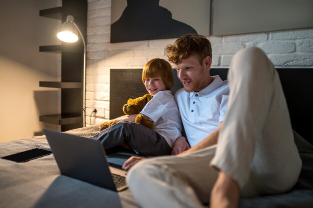Antes de dormir. Pai e filho deitados na cama assistindo algo na internet antes de dormir