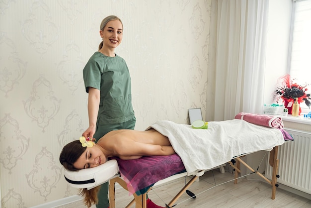 Antes do procedimento de massagem profissional, cosmetologista feminina em pé perto de seu cliente