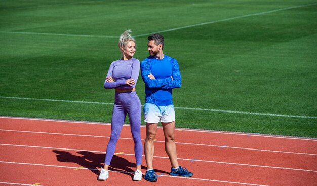 Antes do treino, o casal esportivo e esportista é um bom parceiro de fitness da equipe, homem e mulher atléticos relaxam após a corrida, treinador masculino e feminino no estilo de vida saudável da arena da pista de corrida do estádio