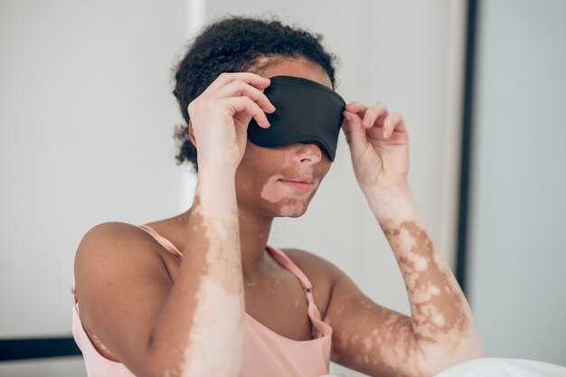 Antes de dormir. Una mujer joven poniéndose una máscara para dormir