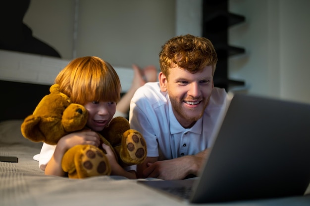 Antes de dormir. Padre e hijo acostados en la cama y viendo algo en internet antes de irse a dormir