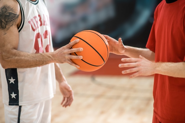 Antes del juego. Dos hombres en ropa deportiva con una pelota antes del juego.