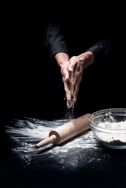 Antes de que termine. Cerca de las manos del joven preparar la harina antes de hornear mientras se cocina en un restaurante.