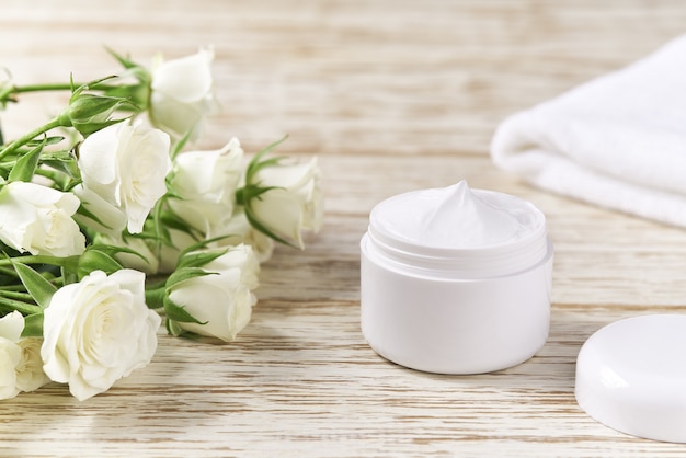 Anti-Falten-Anti-Aging-Creme für empfindliche Haut oder Gesichtspflege-Hygiene-Feuchtigkeitslotion in Plastikdose mit Handtuch auf Holztisch.