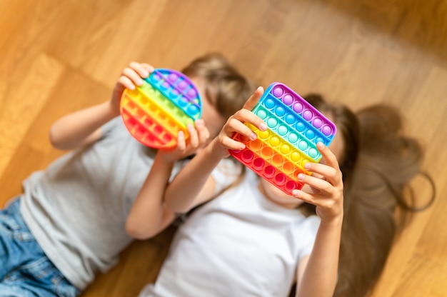 Anti-Stress-sensorisches Pop-Spielzeug in Kinderhänden Ein kleines glückliches Kind spielt mit einem Spielzeug