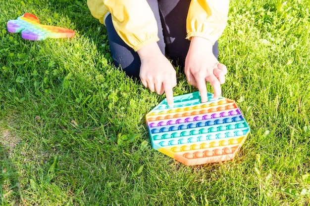 Antiestrés de juguete de arco iris brillante para niños y adultos sobre un fondo de colores. Juguete antiestrés sensorial flexible - popit.