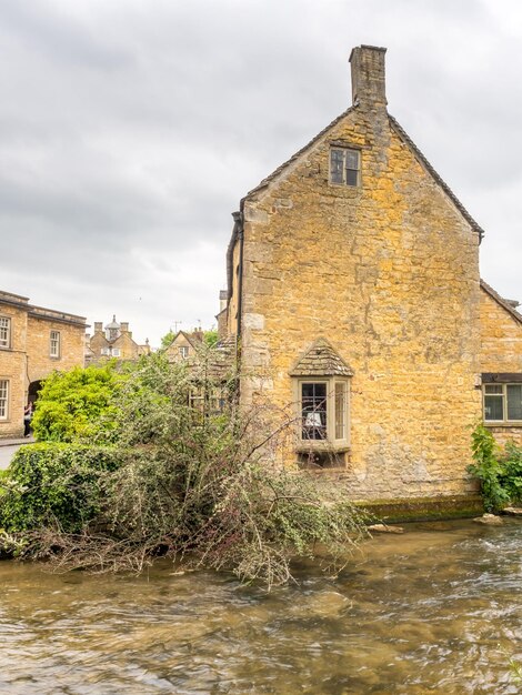 Foto antiga casa de campo inglesa de pedra de estilo clássico em bourton na cidade de água na inglaterra sob céu nublado