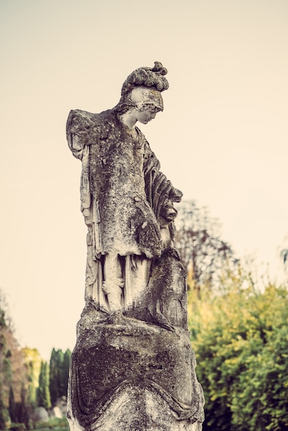 Antiga escultura feminina antiga com céu e árvores