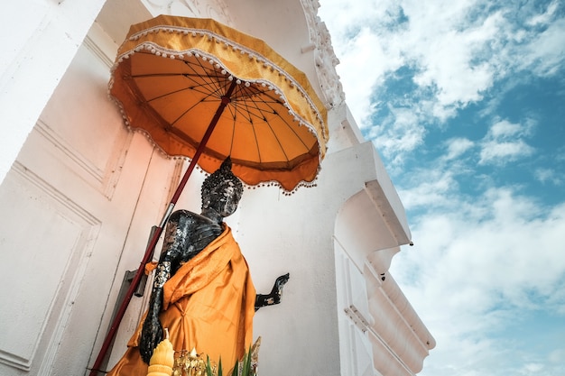 Antiga estátua de Buda tailandês em pé e céu azul