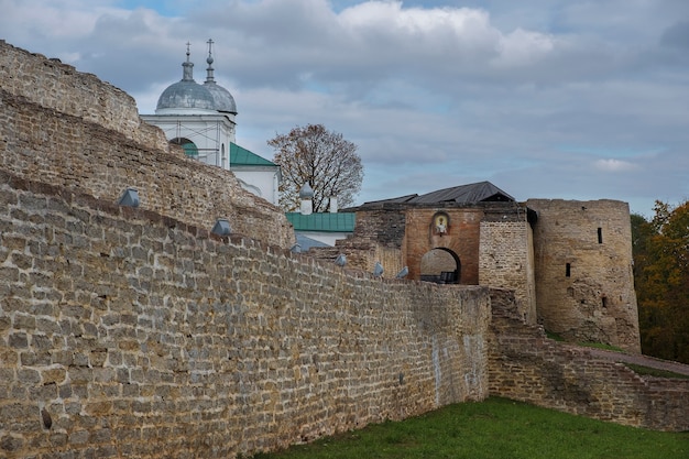 Antiga fortaleza e igreja na pequena cidade de izboursk, região de pskov, na rússia, no outono dourado