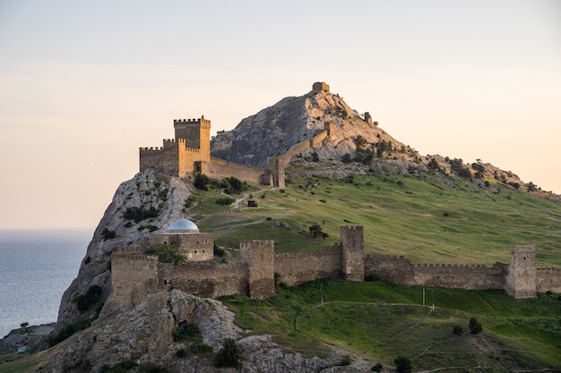 Antiga fortaleza genovesa em uma montanha verde acima do mar azul