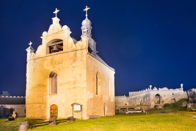 Antiga igreja em um castelo medieval à noite sob um céu azul escuro com muitas estrelas