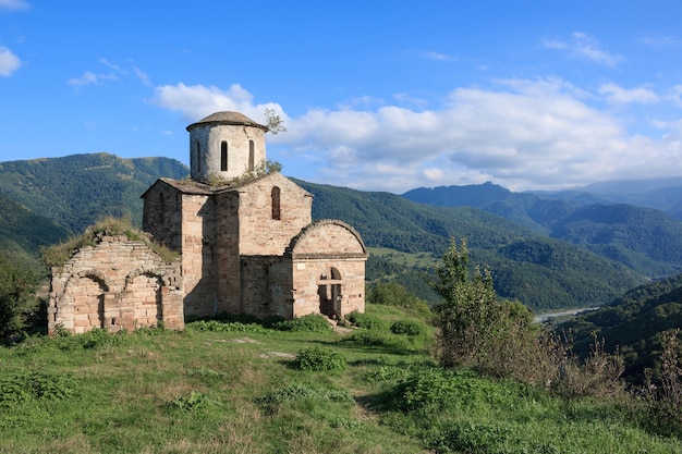 Antiga igreja nas montanhas, no Parque Nacional Dombai, Cáucaso, Rússia. Paisagem de verão, clima ensolarado, céu azul dramático e dia ensolarado