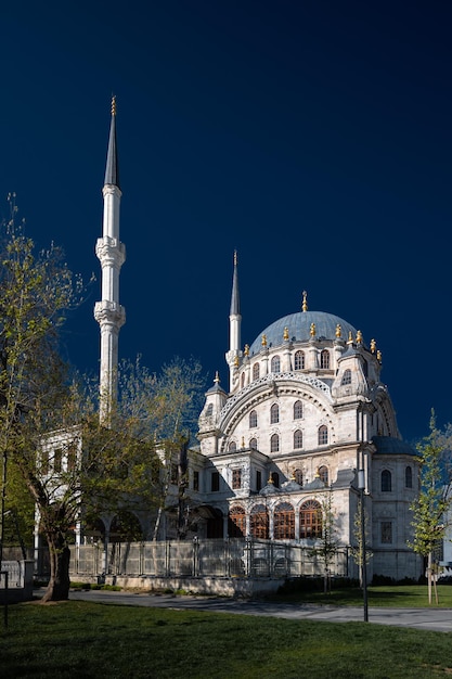 Foto antiga mesquita nusretiye cercada por árvores contra o céu azul escuro em um dia ensolarado em istambul, turquia