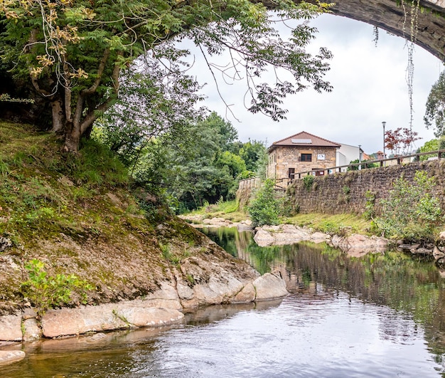 Antiga ponte em arco sobre o rio e abundante vegetação verde