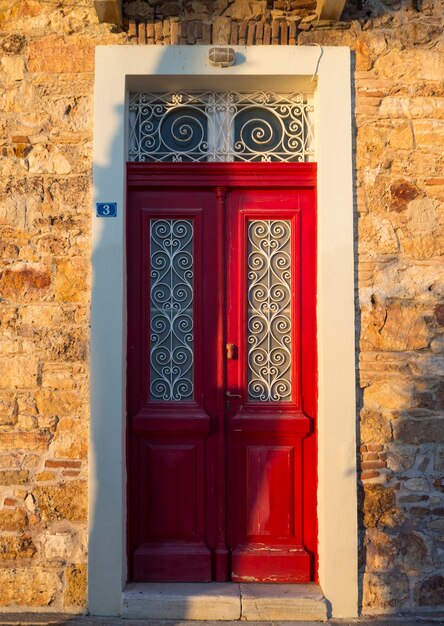 Antiga porta vermelha em uma casa de pedra ao pôr do sol