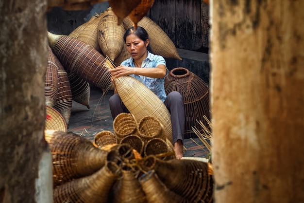 Foto antigo artesão feminino vietnamita, fazendo a armadilha de peixe de bambu tradicional